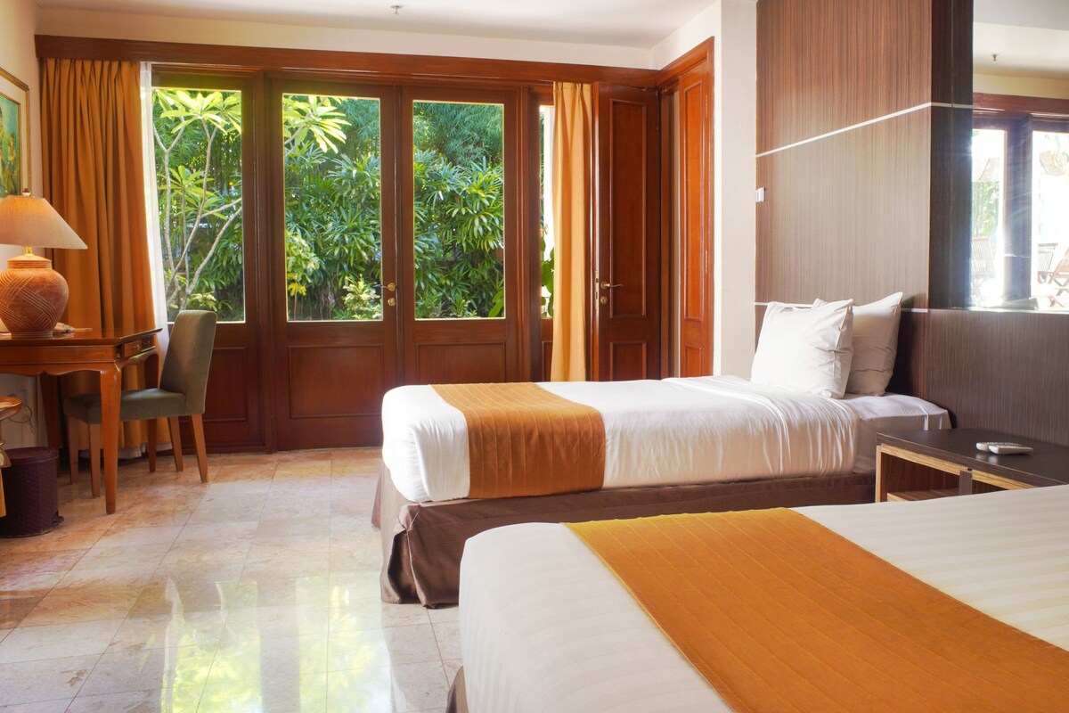 Habitación de hotel con dos camas, un escritorio y una silla.