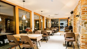 A modern dining area with brick walls, wooden tables, and pendant lighting. - Resort Village Majer - Apartments, Glamping - Slovenia (Gradac)