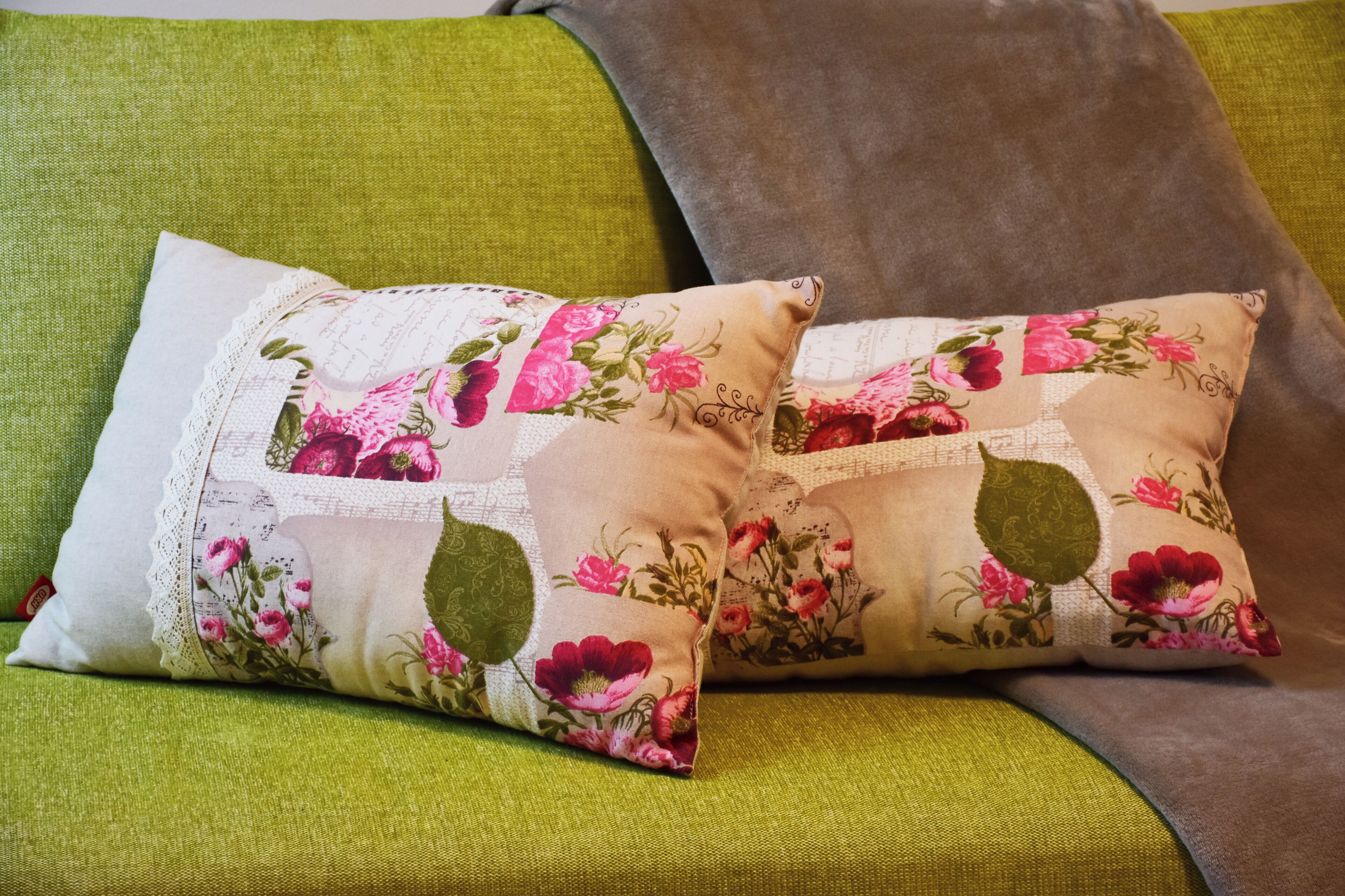 Dos almohadas florales sobre un sofá verde.