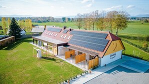 A modern house with solar panels, a large deck, and a view of the countryside. - Resort Village Majer - Apartments, Glamping - Slovenia (Gradac)