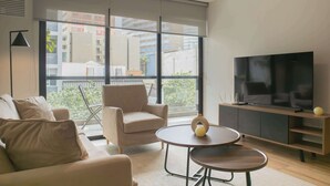 A modern living room with a sofa, armchair, and a TV on a wooden stand.