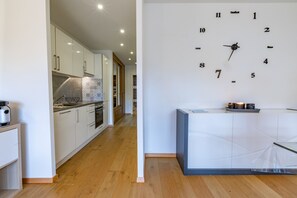 Uma cozinha moderna com armários brancos, piso de madeira e um relógio de parede.