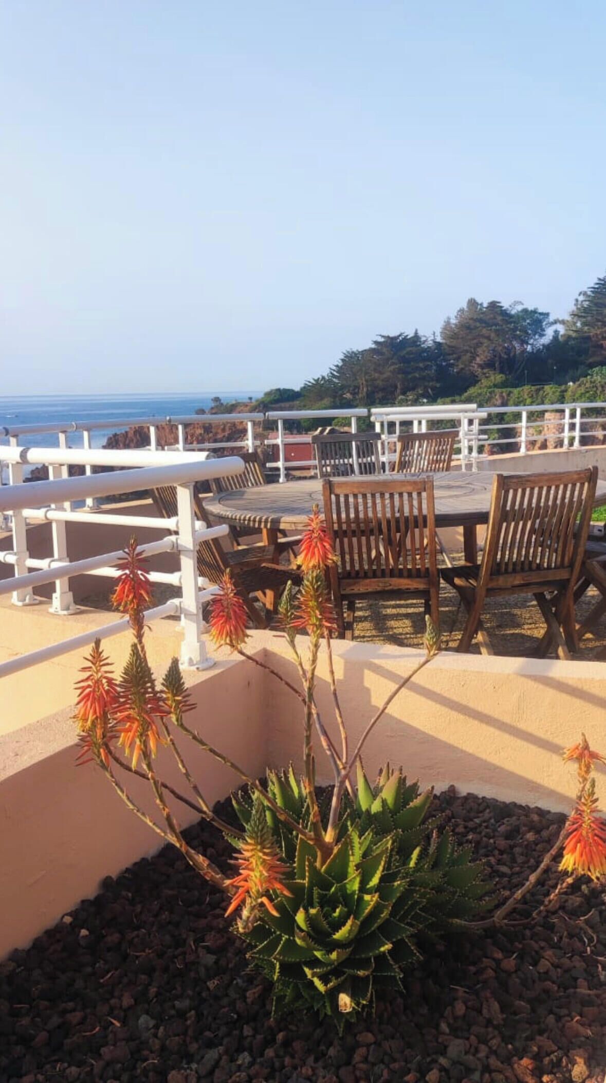 Une terrasse avec une table et des chaises, une balustrade et une vue sur la mer.