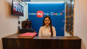 Una recepción con un fondo azul que muestra el logotipo de 'make my trip Google', una pantalla de televisión, un mostrador de madera y un libro rojo.
