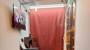 Un mostrador de recepción con un televisor de pantalla plana, un pequeño santuario y una cortina roja al fondo.