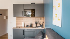 A compact kitchenette with a microwave, coffee maker, and utensils. - Antares Apartments (Düsseldorf)