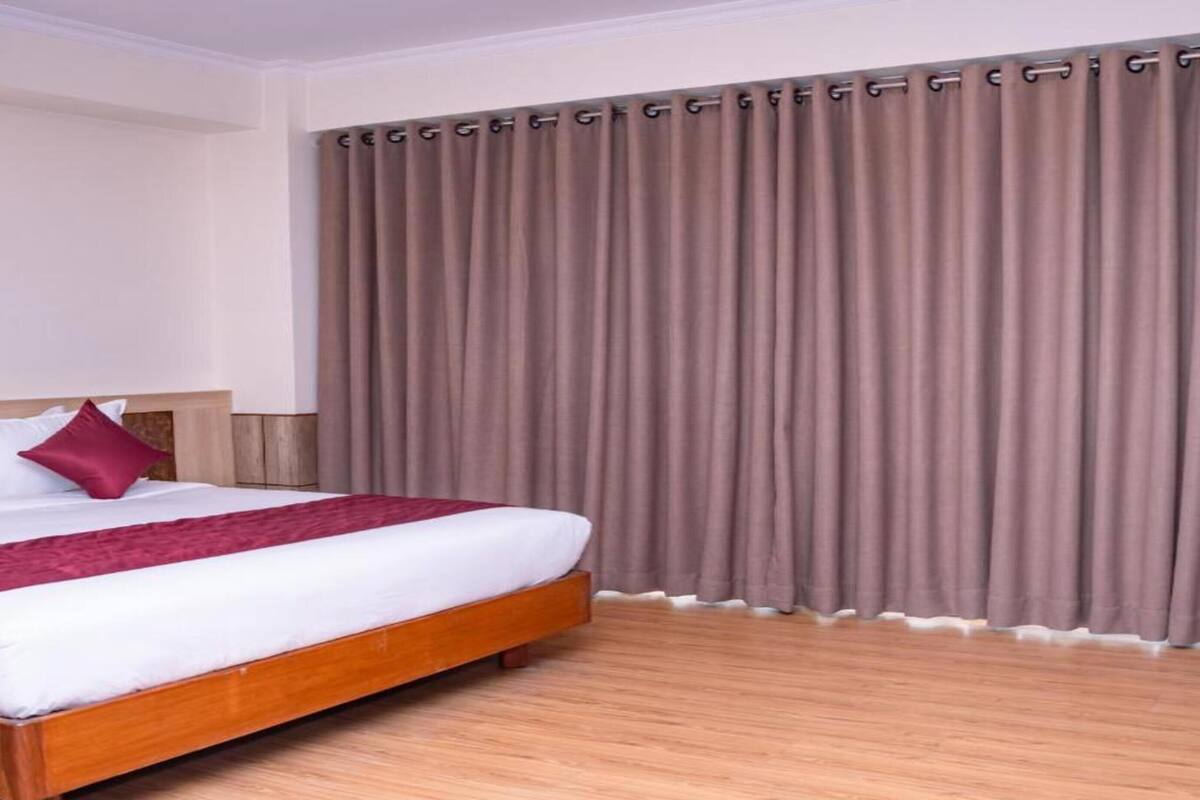 A hotel room with a large bed, wooden headboard, and a wall-mounted light fixture.