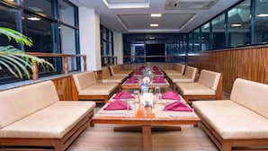 A long dining table with multiple chairs, set with red napkins and a centerpiece. - MeroStay 137 Hotel Eye (Lalitpur)