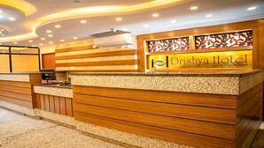 A reception desk at Drishya Hotel with a modern design, featuring a wooden finish and a glass partition. - MeroStay 137 Hotel Eye (Lalitpur)