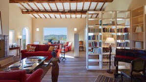 A spacious living room with a red sofa, a coffee table, and a bookshelf filled with books. - Villa Grene - Homelike Villas (Grosseto)