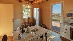 A kitchen with a marble countertop, a stainless steel refrigerator, and a dining table set with glassware and a vase of dried flowers. - Villa Grene - Homelike Villas (Grosseto)