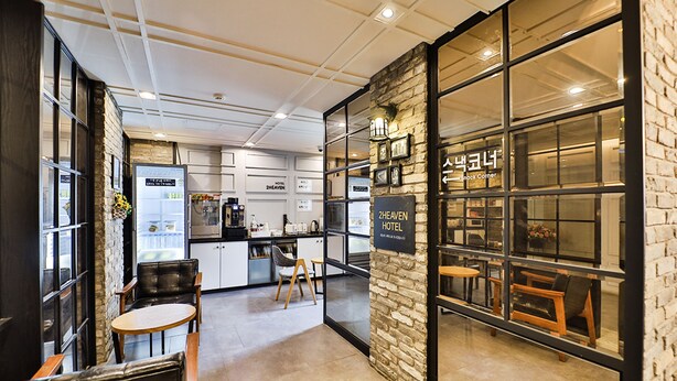 Et moderne hotelværelse med et tekøkken, siddepladser og en stenvæg med et skilt.