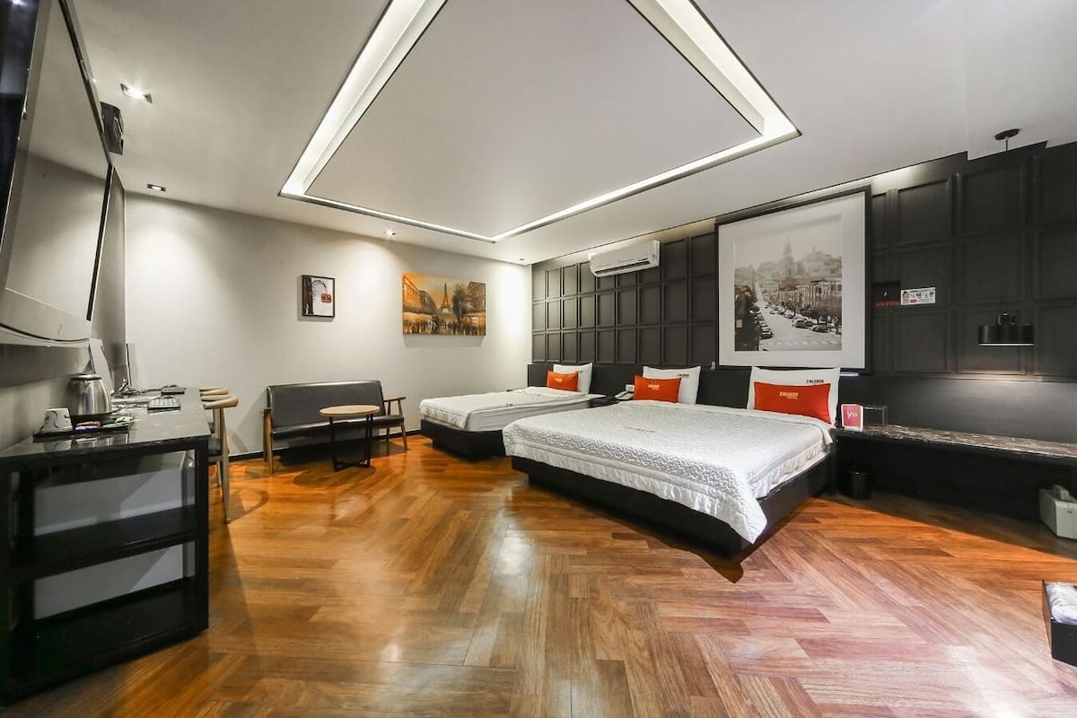 A modern hotel room with a large bed, a desk, and a sofa.