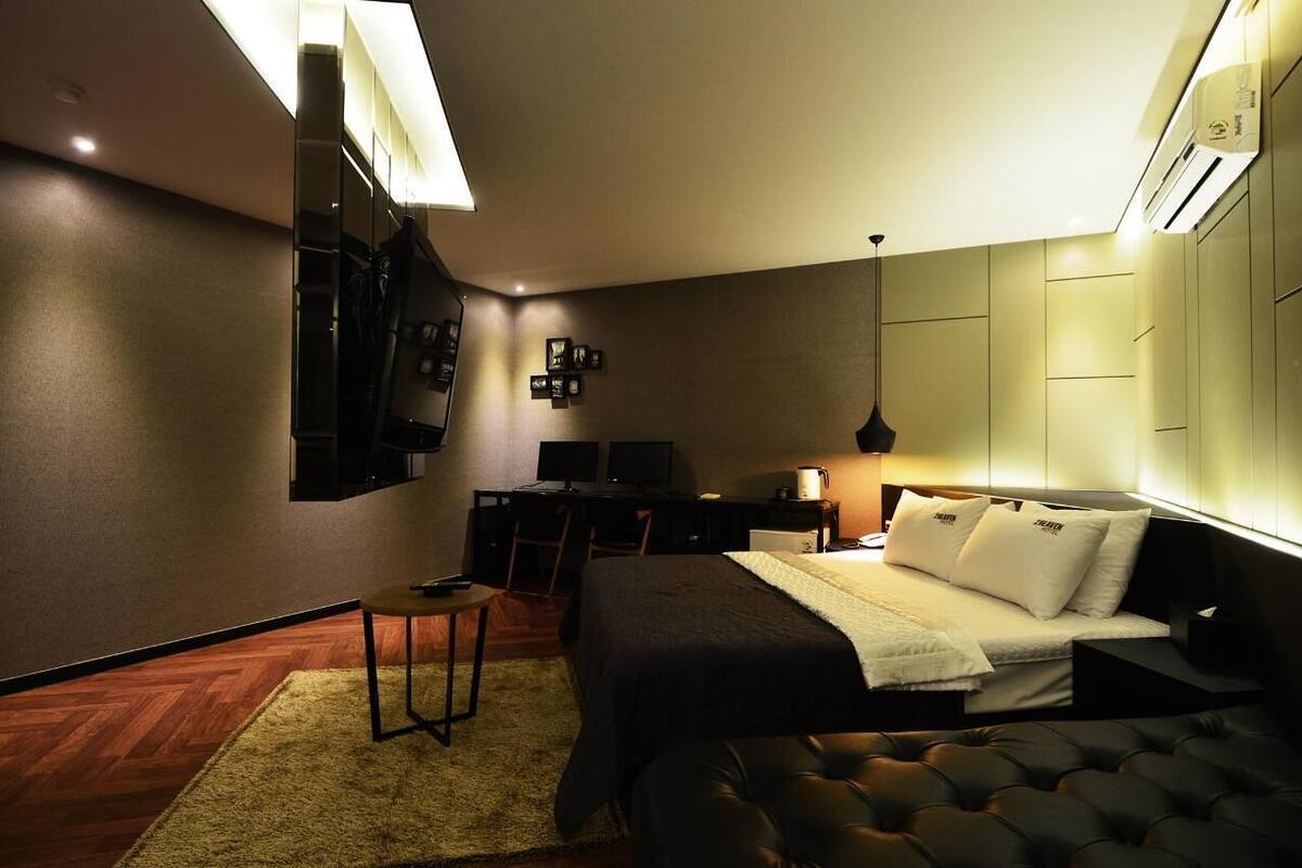 A modern hotel room with a bed, desk, and seating area.