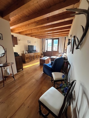 A wooden interior with a sofa, a television, and a dining area.