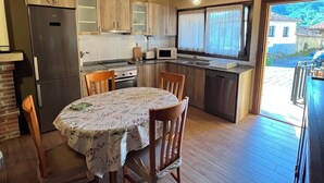 A wooden interior with a dining table, chairs, a refrigerator, a microwave, and a sink. - HOUSE IN THE VILLAGE OF CIRIEÑO (Cirieño- Amieva)