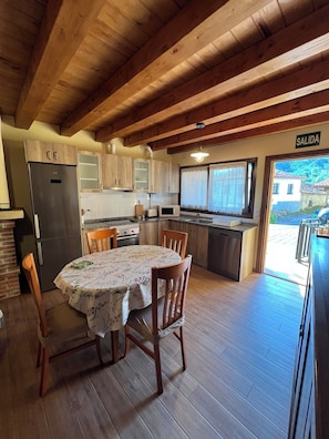 A wooden interior with a dining table, chairs, a refrigerator, a microwave, and a sink.
