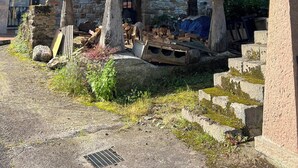 A rustic stone building with a wooden balcony and a staircase leading to an upper level. - HOUSE IN THE VILLAGE OF CIRIEÑO (Cirieño- Amieva)