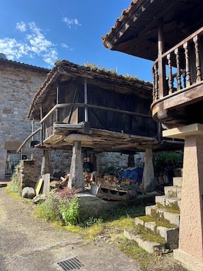 A rustic stone building with a wooden balcony and a staircase leading to an upper level.