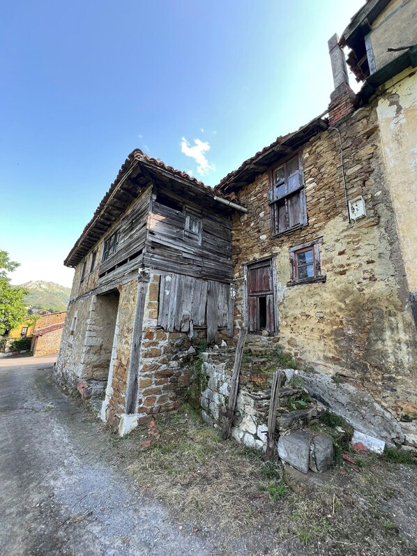 Un vieux bâtiment en pierre, doté de fenêtres en bois et d’une façade patinée par les intempéries.