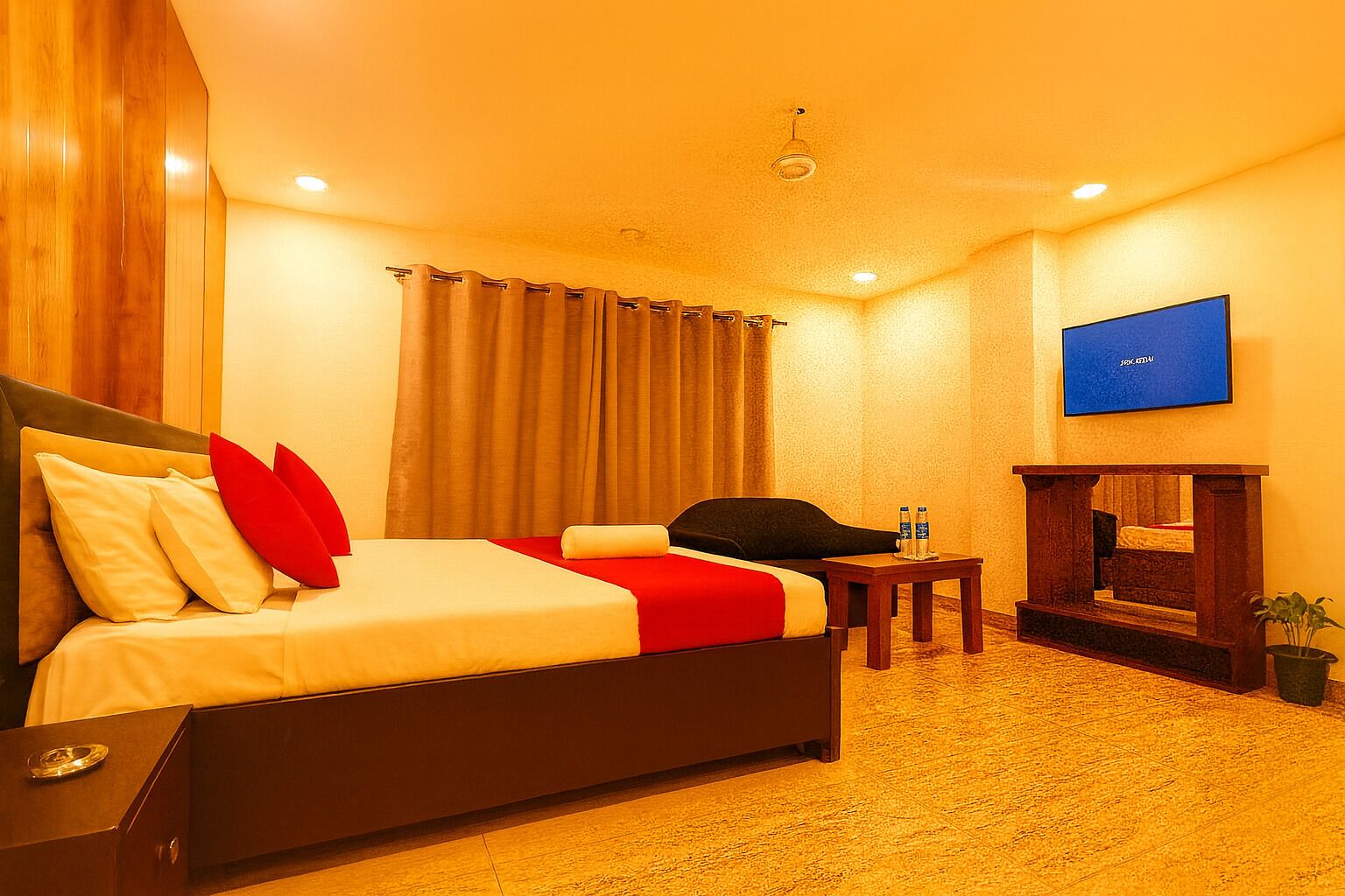 A hotel room with a bed, a chair, a small table, a TV, and a fireplace.