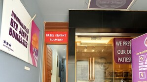 A modern interior with a staircase leading to a glass door entrance, a sign for 'REEL STARHT BOVENEN', and a 'FRESH' sign on the steps. - Mauryan Elite Hotel @ Devli Khanpur (New Delhi)