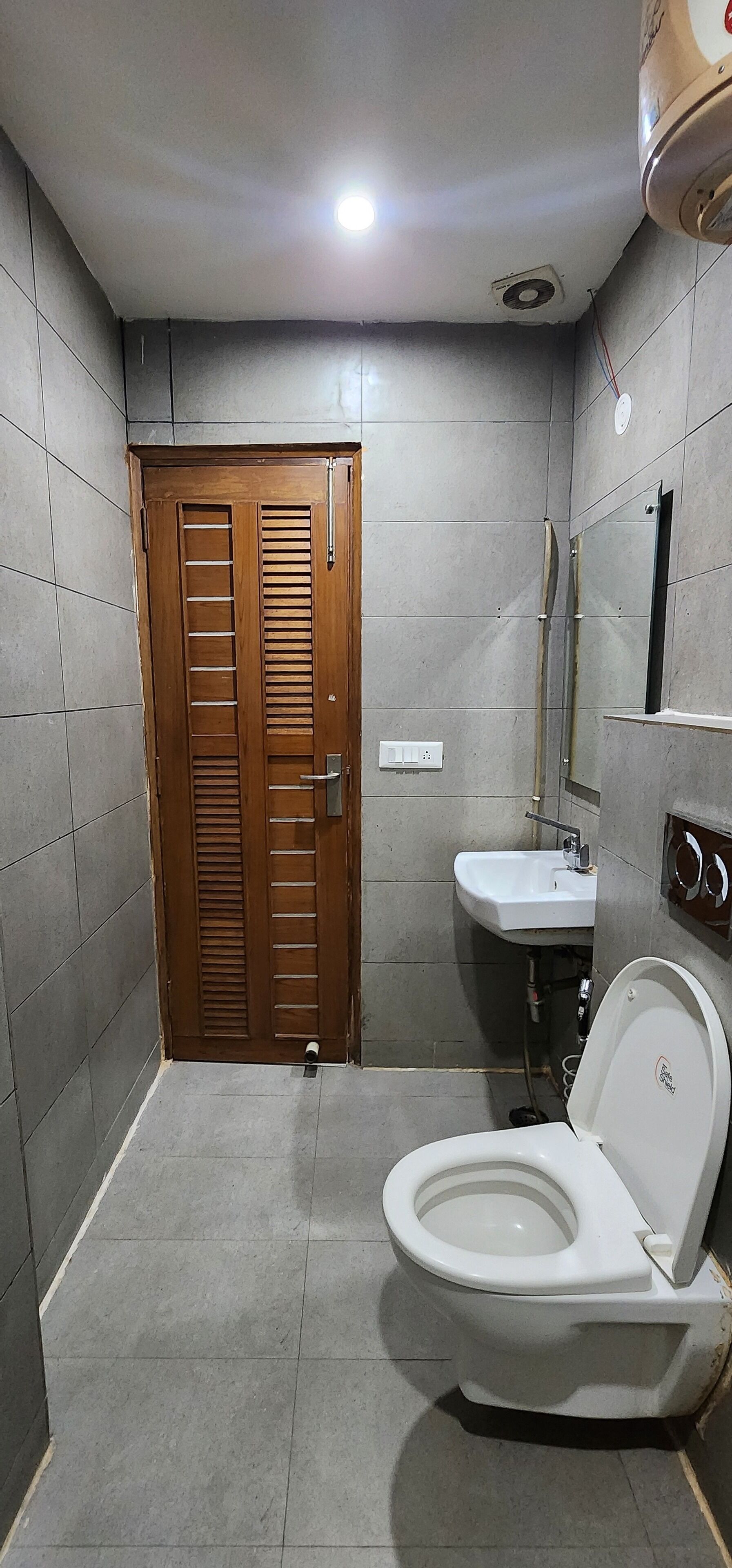 A bathroom with a wooden door, a white sink, and a toilet.