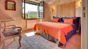 A bedroom with a bed, a chair, a window, and a radiator. - When heritage, art and well-being meet (CANDES SAINT MARTIN)