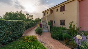 A building with a staircase leading to a door, surrounded by greenery and a brick pathway. - Holiday Apartment 'Casa Vacanze Amarena' with Terrace, Balcony & Shared Pool (olbia)