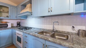 A kitchen with light blue cabinets, a double sink, a stove, and a microwave. - Holiday Apartment 'Casa Vacanze Amarena' with Terrace, Balcony & Shared Pool (olbia)