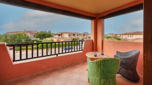 A balcony with a view of houses, a table with chairs, and a railing. - Holiday Apartment 'Casa Vacanze Amarena' with Terrace, Balcony & Shared Pool (olbia)