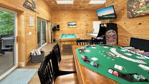 Un interior de madera con mesa de billar, mesa de blackjack y televisor montado en la pared.