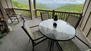 Un balcon avec une table et des chaises, donnant sur un paysage montagneux.