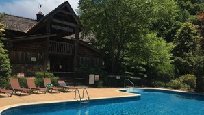 Une piscine avec des chaises longues et un bâtiment en bois doté d’un toit en pente.