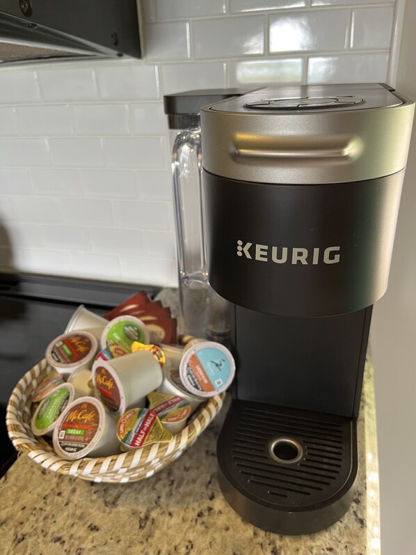 A Keurig coffee maker with a basket of McCafé pods on a kitchen counter.