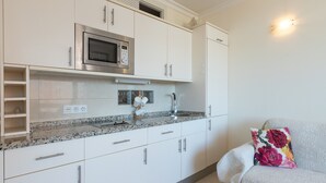 Een moderne keuken met witte kasten, een ingebouwde magnetron en een granieten aanrecht.