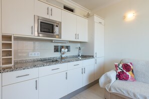 A modern kitchen with white cabinets, a built-in microwave, and a granite countertop.