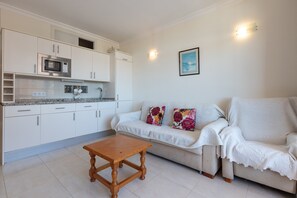 A kitchen with white cabinets, a microwave, and a wooden table.