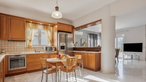 A modern kitchen with wooden cabinets, a dining table, and chairs. - Palailimnos Apartment with Sea View, Wi-Fi, and Air Conditioning (Palelimnos)