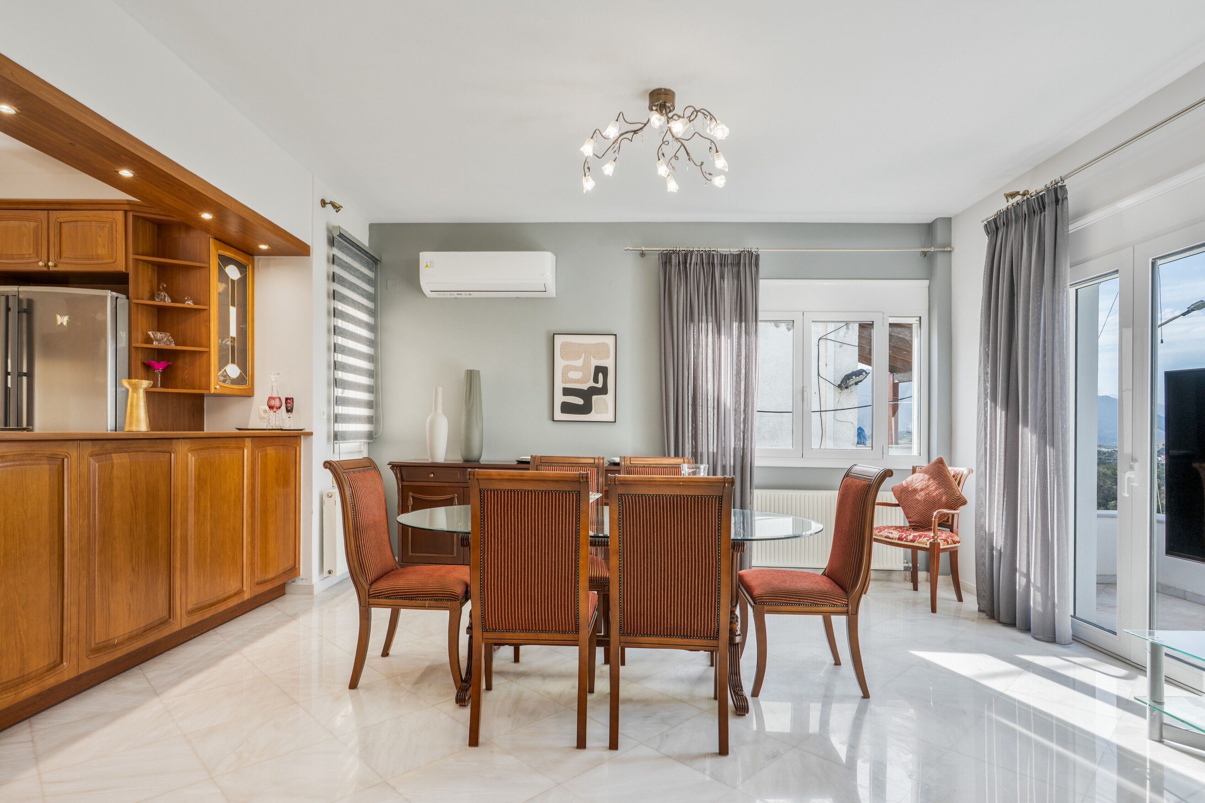 Una cocina moderna con armarios de madera, una mesa de comedor con sillas y un amplio ventanal con cortinas.