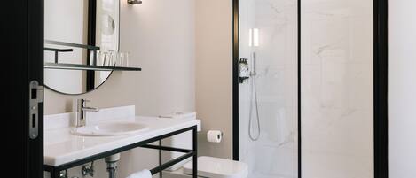 Un baño moderno con ducha de vidrio, lavamanos blanco y espejo sobre la encimera.