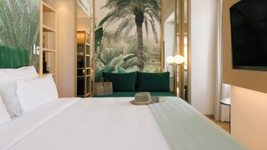A hotel room with a large bed, a tropical mural, a wardrobe, and a TV. - Pestana Rua Augusta - Lisboa (Lisbon)