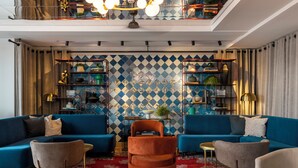 A modern living room with blue sofas, a red patterned rug, and a geometric patterned wall. - Pestana Rua Augusta - Lisboa (Lisbon)