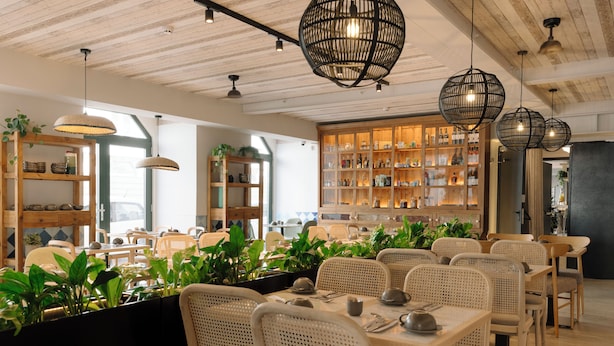 A restaurant interior with wooden ceiling beams, wicker furniture, and a variety of plants. - Pestana Rua Augusta - Lisboa (Lisbon)