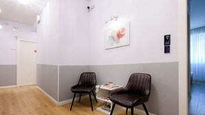 A modern waiting area with two leather chairs, a small table with a book and a plant, and a wall-mounted artwork. - Domus Uffizi (Florence)