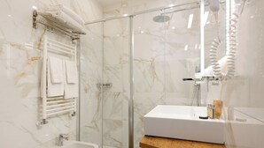 A modern bathroom with a glass shower enclosure, a white sink with a wooden countertop, and a white bidet. - Domus Uffizi (Florence)