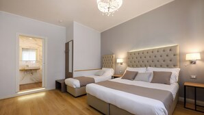 A modern hotel room with a large bed, two smaller beds, a vanity with a mirror, and a chandelier. - Domus Uffizi (Florence)