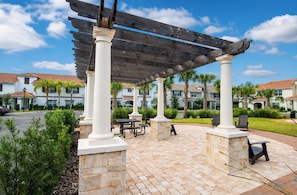 A covered outdoor area with stone columns, picnic tables, and benches.