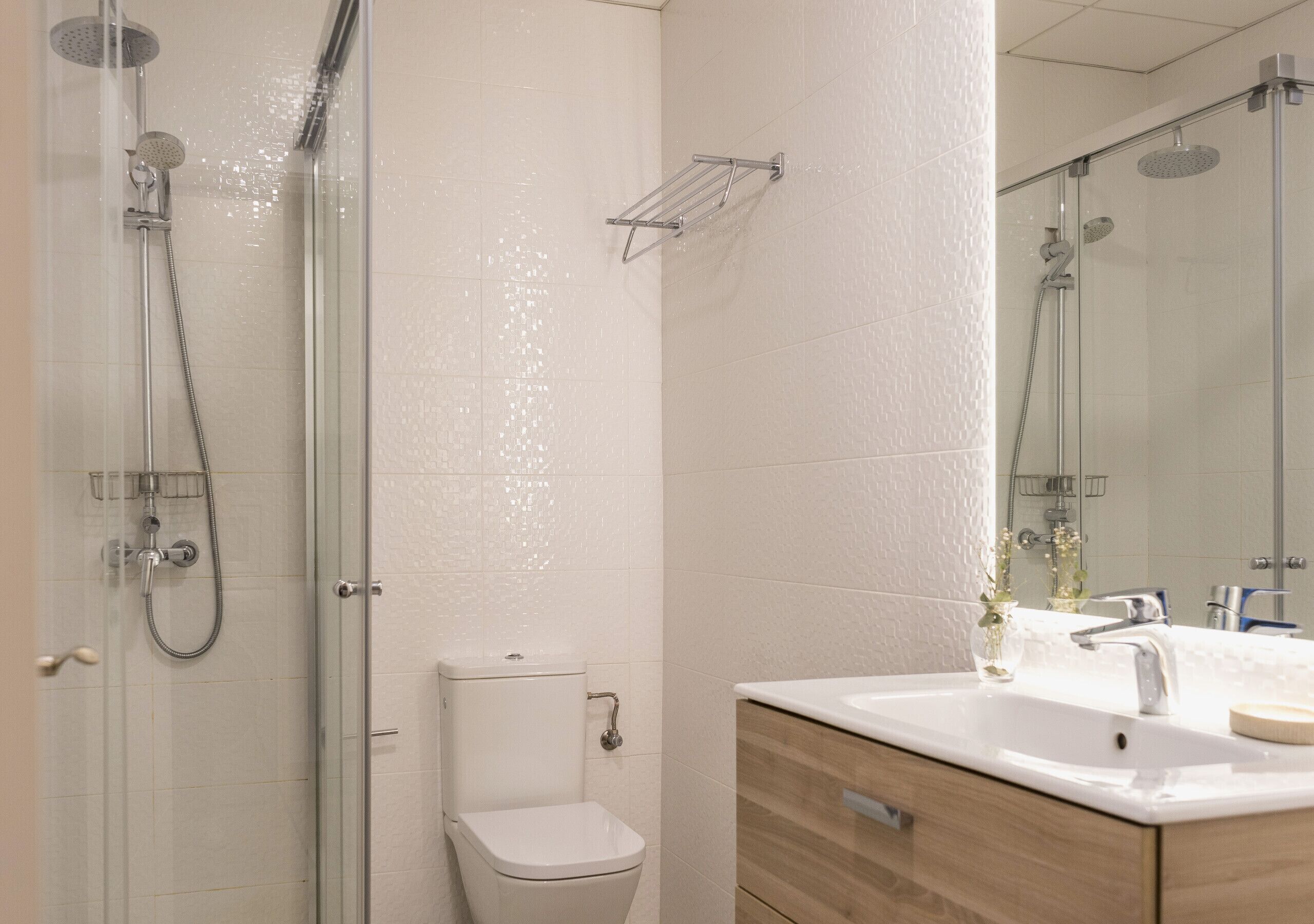 Une salle de bain moderne avec une douche à parois de verre, des toilettes blanches et un meuble-lavabo en bois avec un évier.