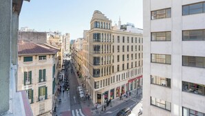 Straßenansicht mit einer Mischung aus historischen und modernen Gebäuden, darunter ein markantes Eckgebäude mit großen Fenstern und einer glatten Fassade.